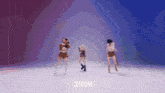 three women are dancing in front of a sign that says choom on it