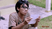 a man wearing glasses is holding a piece of paper with the word wan laksa on it