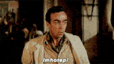 a man in a tan jacket says imhotep in front of a crowd