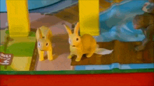 two toy rabbits are standing next to each other in a toy house