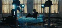 a man sits on a bed in a dark room with a clock on the wall