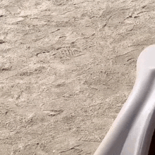 a person is standing on a sandy beach with a white chair in the foreground .