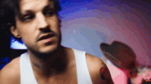 a man in a white tank top looks at something