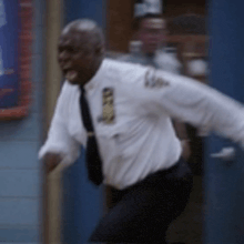 a man in a white shirt and tie is running in a room .