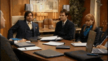 a man in a suit sits at a table with other people