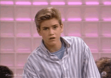 a young man in a striped shirt is making a funny face .