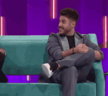 a man in a suit sits on a blue couch