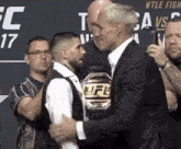 a man with a ufc belt stands next to another man