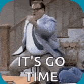 a man in a suit and tie is jumping in the air with the words it 's go time written below him