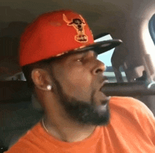 a man with a beard wears an orange shirt and an orange hat with a bull on it