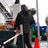 a man in a black jacket is walking in front of a camera