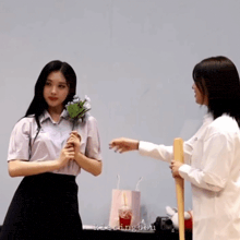 a girl holding a bouquet of flowers next to another girl who is holding a bat