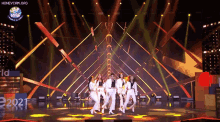 a group of women are dancing on a stage with a honeycam.org logo in the background