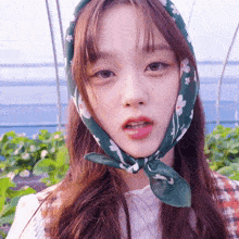a girl wearing a green scarf around her head looks at the camera
