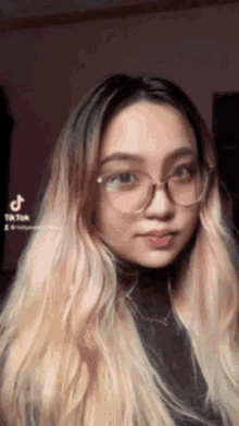 a woman wearing glasses and a black turtleneck looks at the camera with a tiktok watermark in the corner