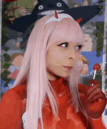 a girl with pink hair is holding a lollipop in front of a totoro