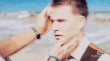 a man in a suit and tie is being touched by another man on the beach .