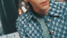 a close up of a person 's face wearing a plaid jacket and earrings .