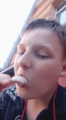 a young boy is eating a marshmallow with a shirt that says urum