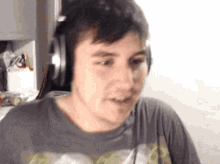 a man wearing headphones and a gray shirt is making a funny face