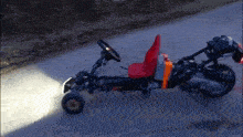 a go kart that looks like a motorcycle with a red seat and steering wheel