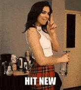 a woman wearing a plaid skirt and a white top is holding a bottle of water .