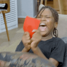 a child is laughing while holding a red card