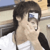 a young man is taking a picture of himself with his cell phone .