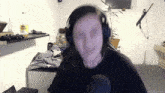 a woman wearing headphones looks at the camera in front of a microphone