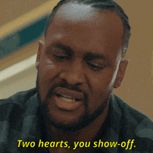 a man with a beard is saying two hearts you show off