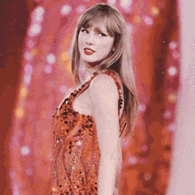 a woman in a red sequined dress is standing in front of a pink background