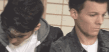 two young men are standing next to each other and one of them is looking down