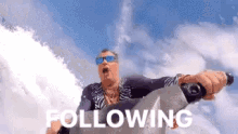 a man wearing sunglasses is riding a jet ski with the words following behind him