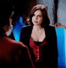 a woman in a red top and black jacket is looking at a man in a red shirt .