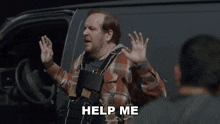 a man in a plaid shirt with a vest that says help me on it