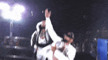 two men are dancing in front of a crowd and one of them is wearing a white shirt that says ' a ' on it