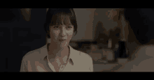 a woman is talking to a man in a kitchen while looking down .