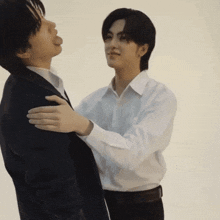 a man in a suit and white shirt is hugging another man