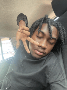 a man with dreadlocks is giving the peace sign