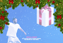a man in a white shirt stands in front of a christmas tree and a gift box with a pink bow