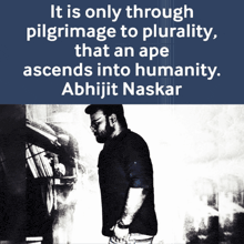 a man stands in front of a sign that says it is only through pilgrimage to plurality that an ape ascends into humanity