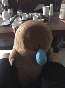 a brown teddy bear with a blue ball in its mouth