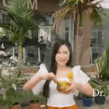 a woman is holding a pineapple in her hands while standing in front of a building .