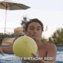 a shirtless man is holding a yellow ball in a swimming pool .