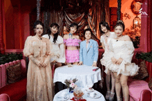 a group of women are posing for a picture in front of a table with flowers on it .