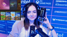 a woman is holding a monster energy drink in front of a microphone