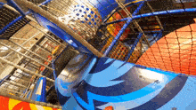 a child is playing in an indoor playground with a blue and red slide