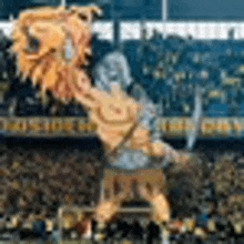 a statue of a man holding a lion 's head in front of a crowd of people in a stadium .