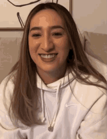 a smiling woman wearing a white nike hoodie