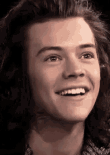a close up of a young man with long hair smiling and looking up .
